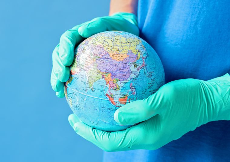 A person wearing gloves holding globe